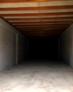 Daylight from the entrance hole reaching only a few feet into a swiftlet house, nesting planks overhead, darkness beyond - MDK Swiftlet