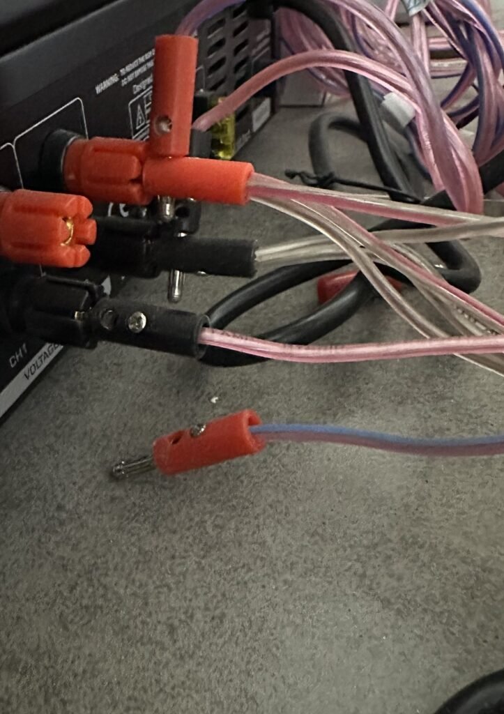 Speaker wires plugged into the output terminals on the back of an amplifier