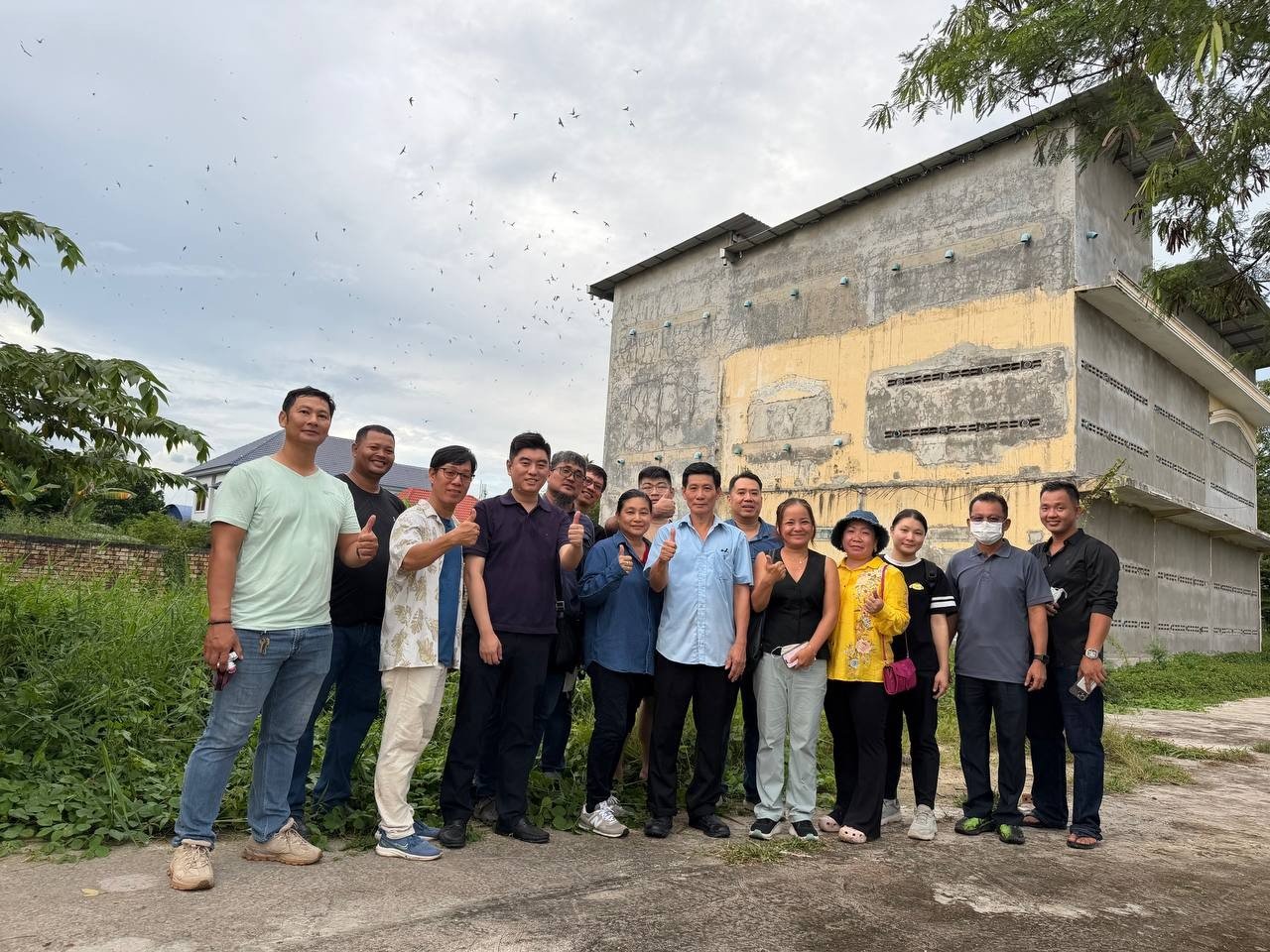 Students standing in front of a swiftlet house, with swiftlets in the sky